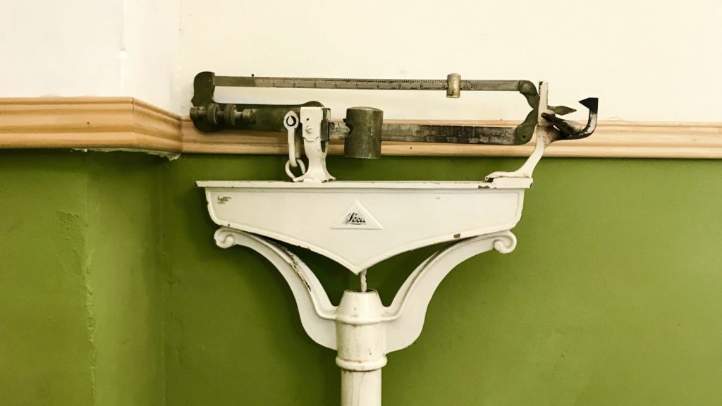 an old fashion scale against a green and white wall